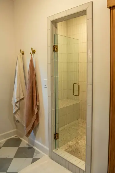Glass shower with tile surround and brass hooks in the primary bath