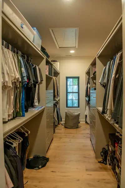 Walk-in closet with custom built-in hanging and shelving on both walls