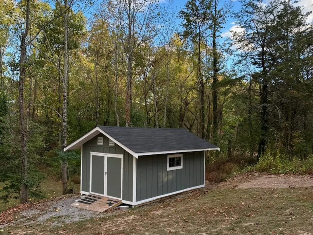 Finished storage shed with dark green board-and-batten siding and white trim